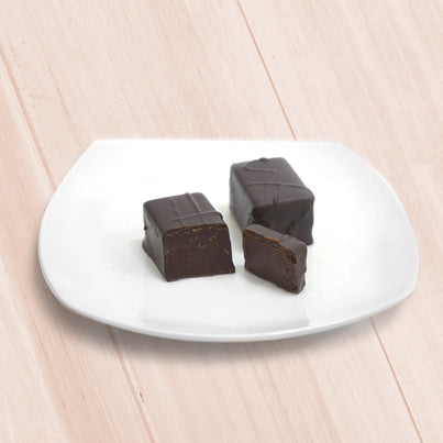 Two cut chocolate bars sit on a white, square plate.