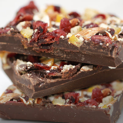 Three bars of the dark chocolate bark stacked vertically. They are topped with bits of orange and cranberry,