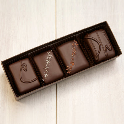 An open four piece assortment. Various chocolates from the assortment are pictured.