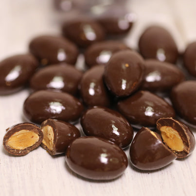 A handful of chocolate covered almonds sit scattered on a table.