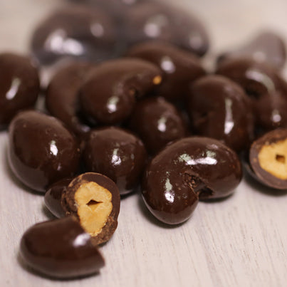 Chocolate covered cashews are sitting everywhere. A few of them are cut in half.