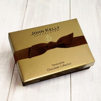 A gold box with a brown ribbon stretched around it.