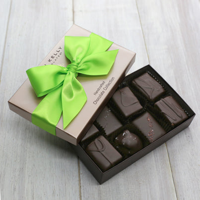 An open eight piece assortment box. The chocolate in the assortment is featured as well as a bright green ribbon.