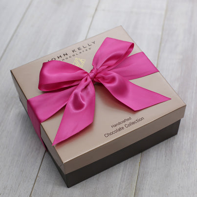 A closed 24 piece assortment with a fuchsia ribbon.