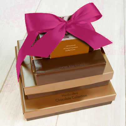 Four boxes stacked vertically from largest to smallest. They are tied together with a fuchsia ribbon.