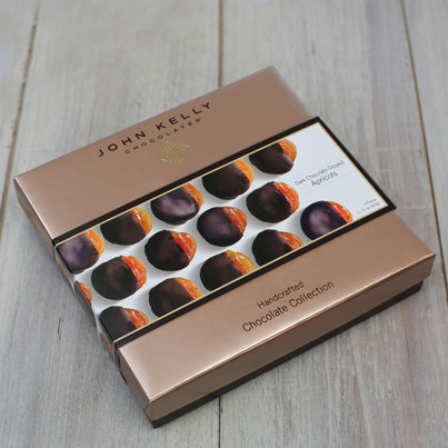 A closed box of the chocolate covered apricots. The sleeve of the box is white and has pictures of the apricots sitting neatly sideways.