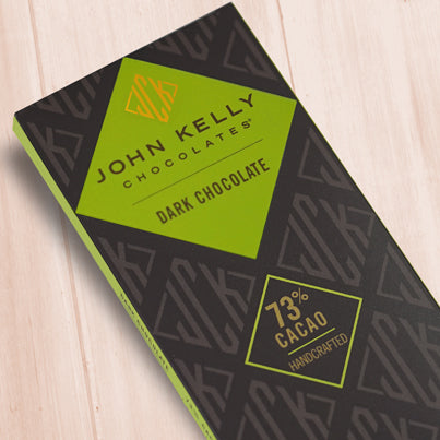 A dark brown, rectangular box. There is a green diamond on it that holds a John Kelly Chocolates logo and the product name.
