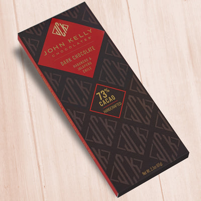 A dark brown, rectangular box. There is a red diamond on it that holds a John Kelly Chocolates logo and the product name.