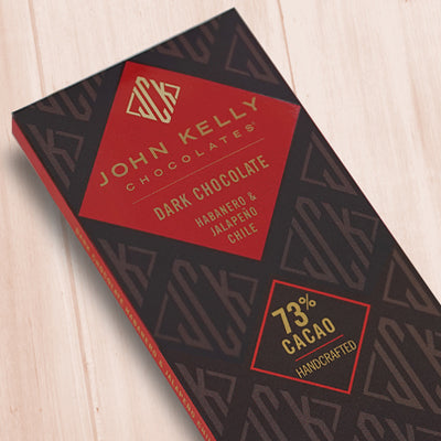 A dark brown, rectangular box. There is a red diamond on it that holds a John Kelly Chocolates logo and the product name.