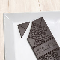 A dark solid bar with the top left corner cut off from it. The bar has a John Kelly Chocolates logo on it.