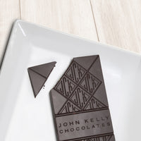 A dark solid bar with the top left corner cut off from it. The bar has a John Kelly Chocolates logo on it.