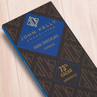 A dark brown, rectangular box. There is a blue diamond on it that holds a John Kelly Chocolates logo and the product name.