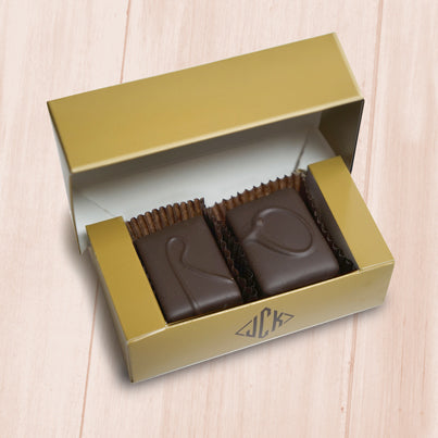 A gold box sits open with two squares of chocolate in it. They are labeled with an O and a R/