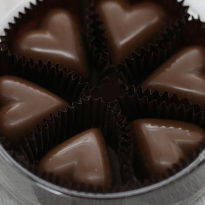 Six milk chocolate pieces sit in a plastic, round container with no lid.