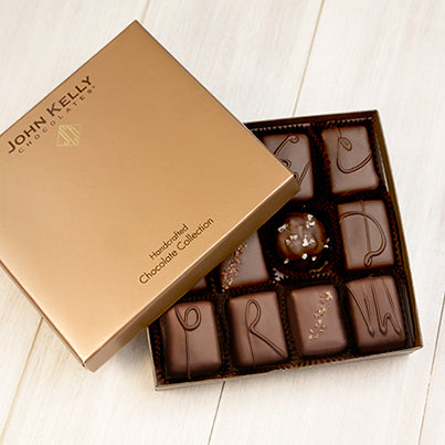An open 12 piece assortment. The light brown lid of the box is partially on the box.