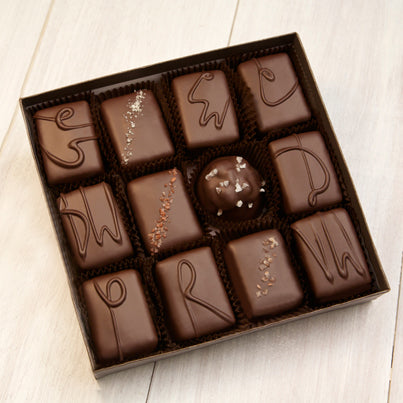 An open 12 piece assortment. Various chocolates from the assortment can be seen neatly placed into the brown box.
