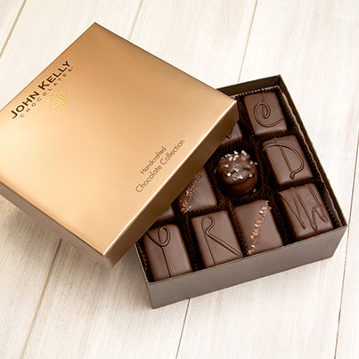An open 12 piece assortment with various chocolates from the assortment. The lid of the box is sitting partially on the box.