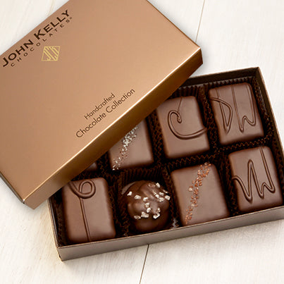An open eight piece assortment. Various chocolates from the assortment can be seen. The lid of the box sits partially on the box.