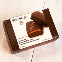 A closed dark brown box with a white sleeve on it. A picture of two red salted chocolate bars is featured.
