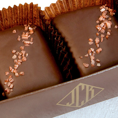 A close up of two red salted chocolate bars in a brown box.