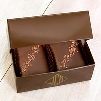 Two red salted chocolates sit in a dark brown box.