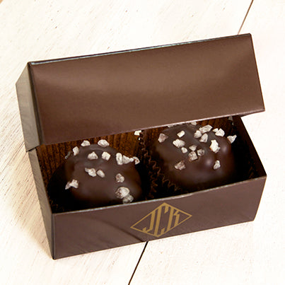 Two salted caramel walnut clusters in a dark brown box.