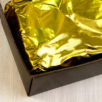 A close up of a gold wrapped in a dark brown box.