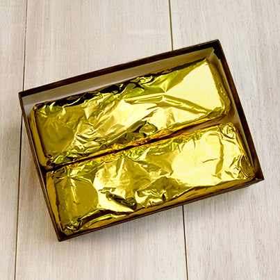 Two gold wrapped rectangular bars in a brown gift box.
