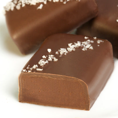 A grey salted truffle fudge bite. It is cut open to reveal the chocolate inside.