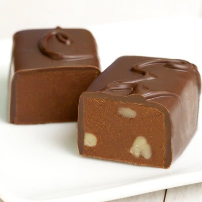 Two chocolates on a plate cut open to reveal chocolate and walnuts.