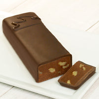 A long rectangular chocolate bar with a CW on it that signifies it is semi-sweet with walnuts. One end of the bar is cut to reveal the chocolate and walnuts inside.