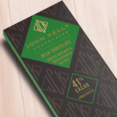 A dark brown, rectangular box. There is a dark green diamond on it that holds a John Kelly Chocolates logo and the product name.