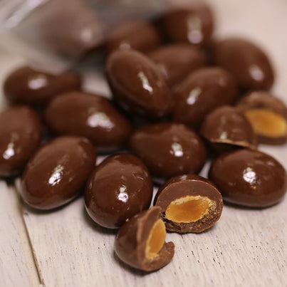 A bunch of chocolate covered almonds. Some of them are cut in half.