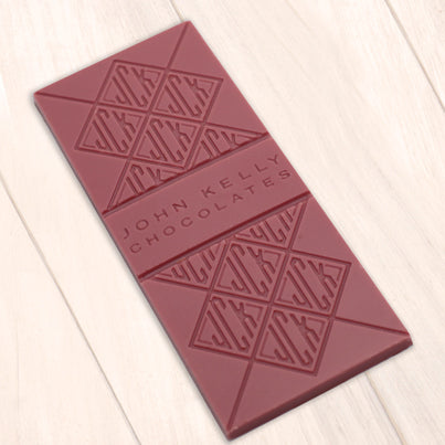 A pink ruby chocolate bar. The bar is molded with the John Kelly Chocolates logo all over it.