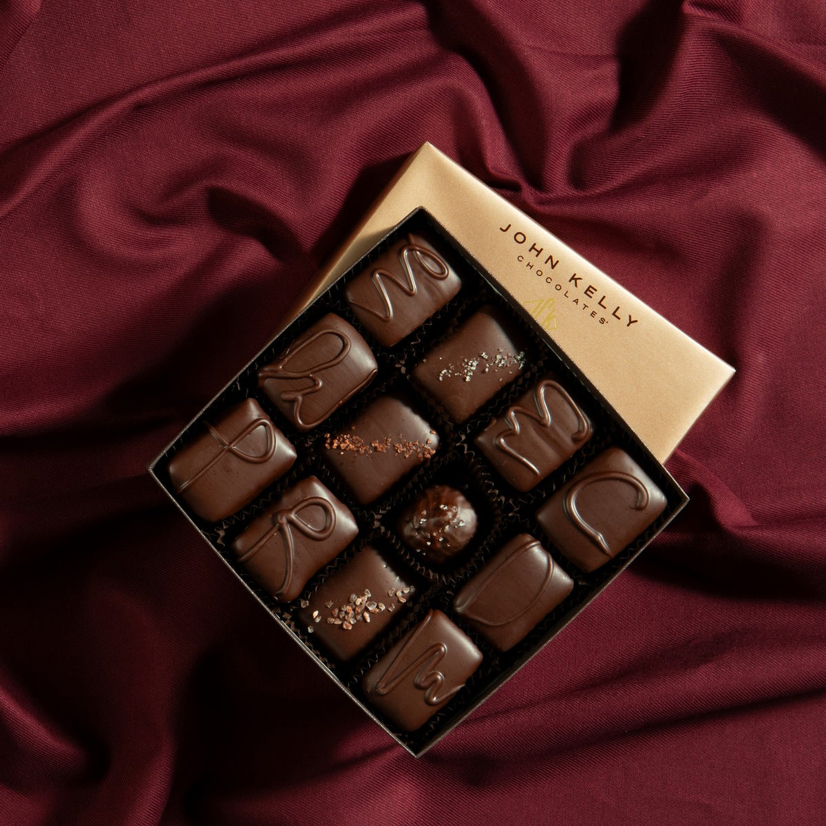 John Kelly Chocolates 12 piece box, open, on burgundy satin