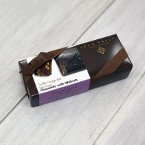 A rectangular, dark brown box with a white chocolate with walnuts sleeve on it. The box has a brown ribbon on it.