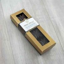 A closed four piece dark butterflies box. The lid of the box is golden with a window, where the dark chocolate butterflies can be seen. The butterflies sit vertically in the long, rectangular box. The label of the box sits three quarters of the way up the box and is white with a John Kelly Chocolates logo on it.