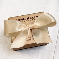 A closed one piece gift box with an off-white ribbon on it.