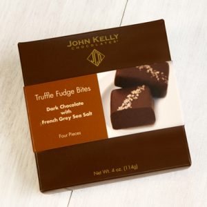 A dark brown box with a brown and white sleeve on it. A picture of two grey salted truffle fudge bites can be seen.