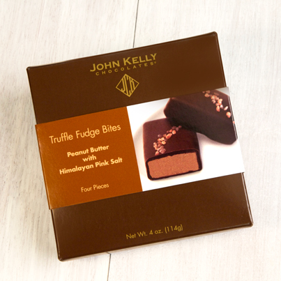 A closed four piece peanut butter pink salt box. The box is a dark brown lighter brown and white sleeve. One side of the sleeve has the label on the left side and a picture of the chocolate on the right,