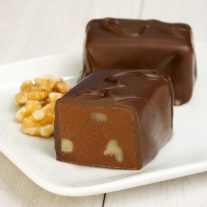Two semi-sweet chocolate bars with walnuts. One is cut in half revealing the chocolate and walnuts inside. Some walnuts sit to the left of the chocolate.