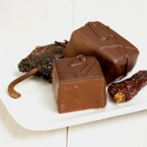 Two chile chocolate bars with chiles around them.
