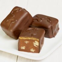 Three semi-sweet chocolate bars with caramel and walnuts sit on a plate.