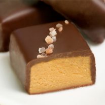 A pink salted truffle fudge bite, cut up to expose the peanut butter inside.