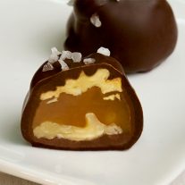 Two salted walnut caramel clusters on a plate. One is cut in half to reveal the caramel and walnuts inside.