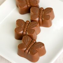 Four milk chocolate butterflies on a white plate.