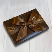 A closed 8 piece assortment with a brown ribbon that reads John Kelly Chocolates. The box is brown with a gold John Kelly Chocolates logo