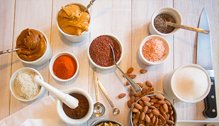 Various salts, spices, and nuts in white bowls.