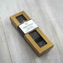 A closed four piece fleur de sel salted caramel box. The box is long and rectangular. The lid of the box is gold with a window where you can see the caramels. The label on the box is three quarters of the way up the box. The label is white and has a John Kelly Chocolates logo on it.