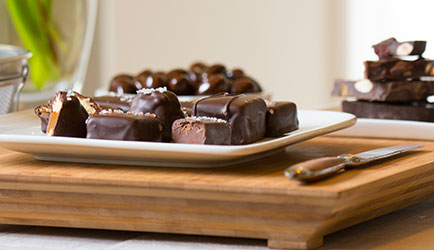 Cut chocolate on a white plate. some chocolate sits in white bowls too.